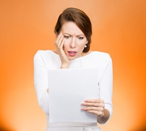 Closeup portrait shocked, funny looking young woman, disgusted at monthly statement, test, application, results isolated orange background. Negative human emotion, facial expression, feeling. Bad news