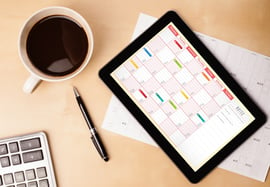 Workplace with tablet pc showing calendar and a cup of coffee on a wooden work table close-up.jpeg