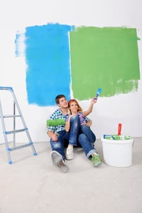 happy young couple relax after painting white wall in green and blue color in their new home