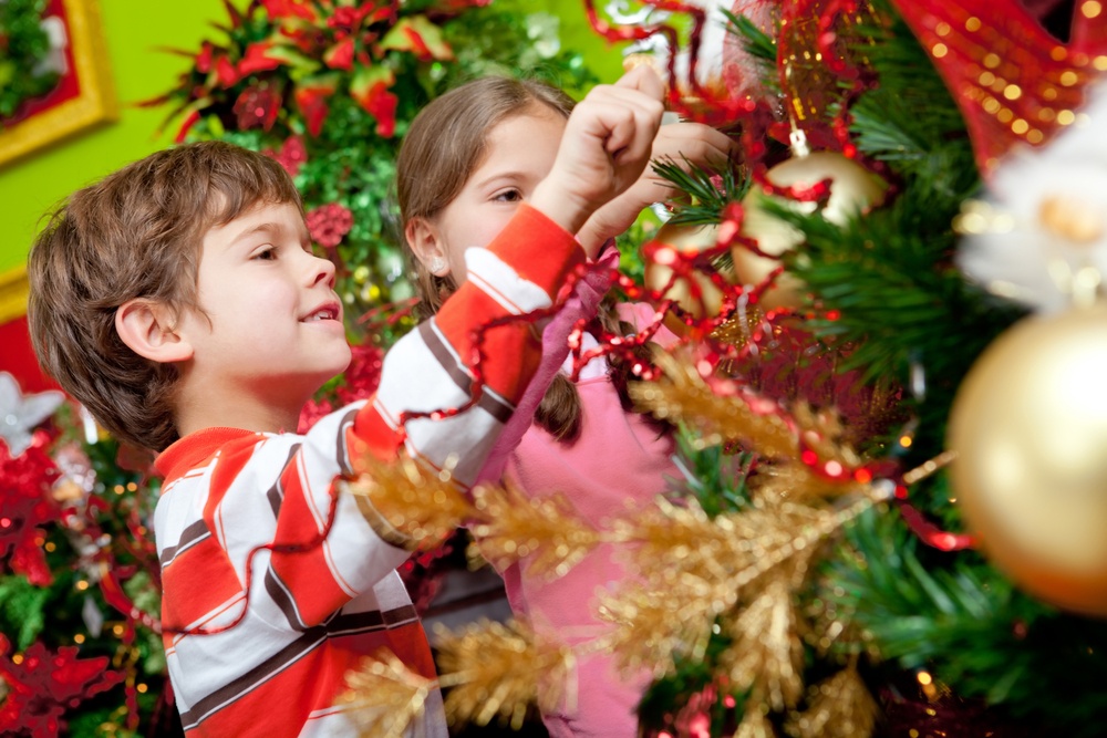 Happy kids decorating a Christmas tree with ornaments.jpeg